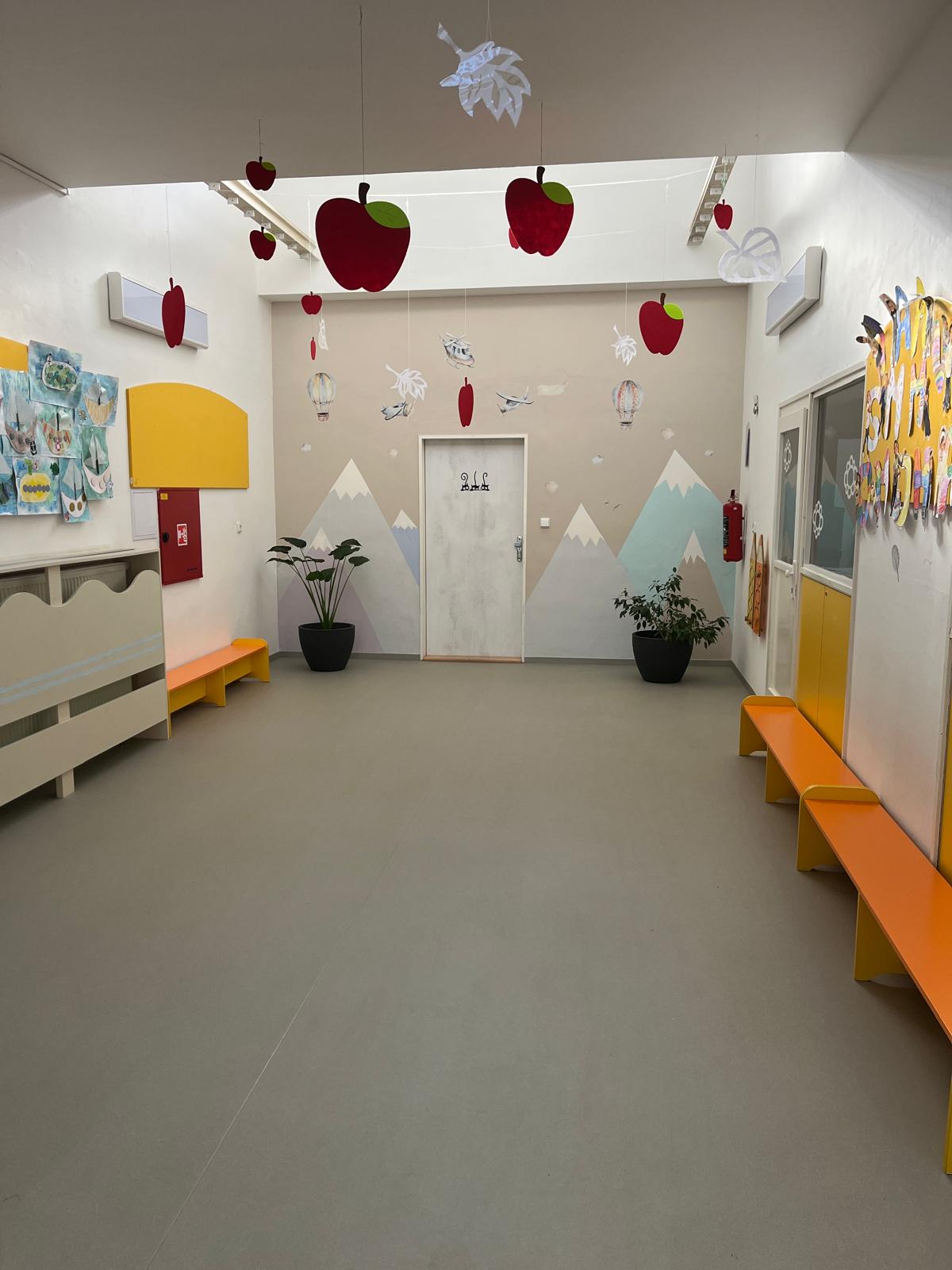 Prostorná školní chodba s výzdobou jablek, horami a dětskými pracemi